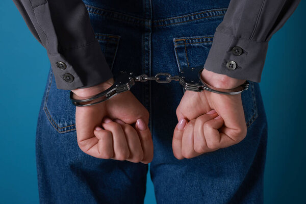 Женщина в металлических наручниках на синем фоне, крупным планом