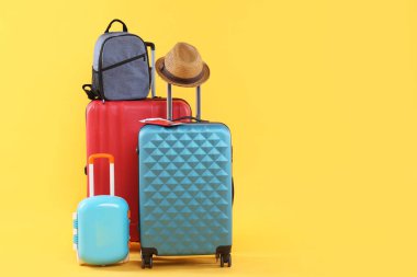 Yurt dışına seyahat et. Paketlenmiş bavullar, sırt çantası ve sarı arka planda şapka, metin için boşluk