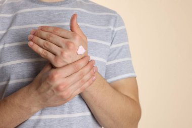 Bej arka planda el kremi süren bir adam, yakın plan. Metin için boşluk