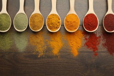 Tahta masadaki kaşıklardaki farklı aromatik baharatlar. Metin için boşluk