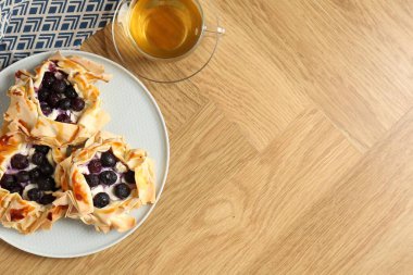 Yaban mersinli nefis puf börekleri ve ahşap masada çay, düz yatak. Metin için boşluk