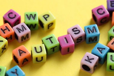 Word Autism made with colorful cubes on yellow background, closeup clipart