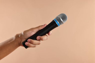 Bej arka planda mikrofonu olan adam, yakın plan.