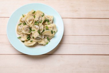 Beyaz ahşap masa üzerinde yeşil soğanlı nefis pelmeni, üst manzara. Metin için boşluk