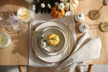 Yemek odasında güzel bulaşık takımları ve sonbahar dekoru olan şık masa ayarları.