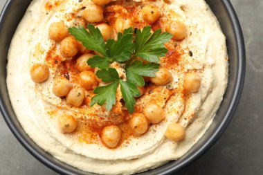 Maydanozlu enfes humus, kırmızı biber ve nohut kasede gri masada, yakın plan.