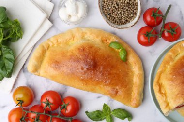 Domatesli lezzetli vejetaryen calzones, mozzarella peyniri ve baharatlar beyaz mermer masada, düz yerde.