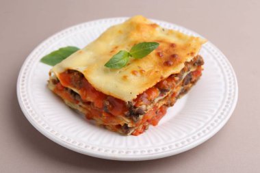 Açık gri masada fesleğenli nefis pişmiş lazanya, yakın plan.
