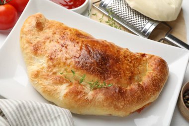 Lezzetli taze calzone pizza ve malzemeler masada, yakın plan.