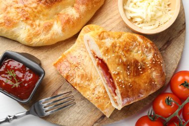 Beyaz ahşap masada servis edilen taze calzone pizza parçaları.