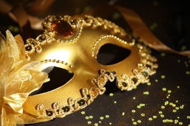 Güzel bir karnaval maskesi, koyu arkaplanda kurdele ve konfeti, yakın plan.