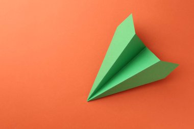 Turuncu arka planda el yapımı yeşil kağıt uçak, üst manzara. Metin için boşluk