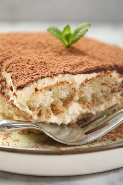 Beyaz mermer masanın üzerinde lezzetli bir tiramisu parçası, yakın plan.