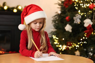 Küçük kız Noel Baba 'ya mektup yazıyor. Noel kutlaması