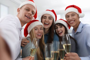 Gülümseyen meslektaşlar ofiste Noel partisinde selfie çekiyorlar.