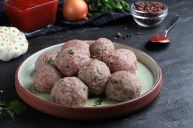Many fresh raw meatballs on black table