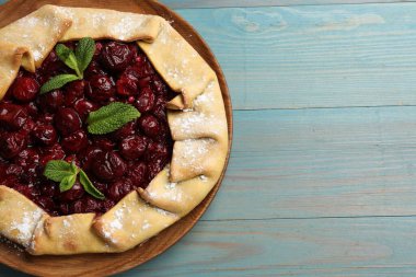 Kirazlı leziz bir galet ve açık mavi ahşap masa, üst manzara. Metin için boşluk