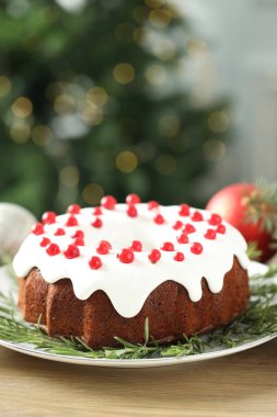 Geleneksel Noel pastası kırmızı frenk üzümü ve ahşap masada biberiye ile süslenmiş.