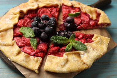 Çilekli, yaban mersinli ve nane şekerli leziz galette açık mavi ahşap masa, yakın plan.