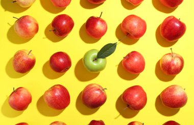 Sarı arkaplanda kırmızı elmalarla çevrili düz kompozisyon.