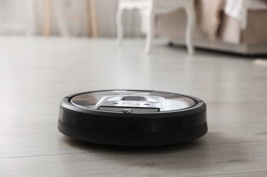 Robotik süpürge, ahşap zeminde, kapalı alanda.