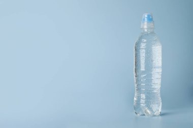 Açık mavi zemin üzerinde plastik su şişesi, metin için boşluk