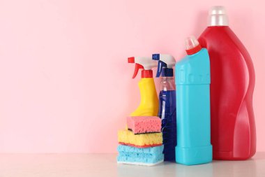 Masadaki farklı temizlik ürünleri ve malzemeler pembe arkaplan, metin için yer