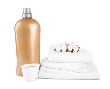 Çamaşır deterjanı, kep, temiz havlular ve beyaz üzerine izole edilmiş pamuk çiçekleriyle dolu bir şişe.