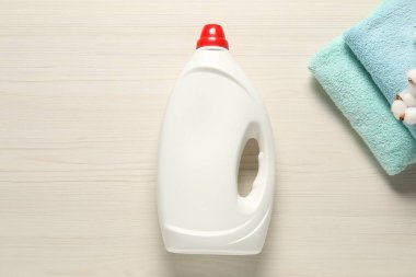 Çamaşır deterjanı ve ahşap arka planda temiz havlularla dolu bir şişe.