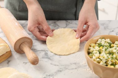 Beyaz mermer masada pirozhki yapan bir kadın, yakın plan.