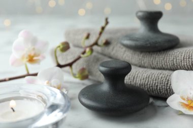 Spa taşları, orkide çiçekleri, havlular ve yanan mumlar beyaz mermer masada, yakın plan.