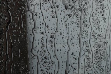 Gri cam yüzeyine su damlıyor, yakın plan.