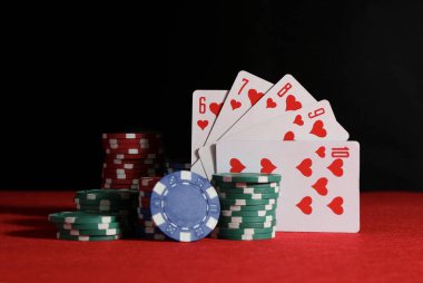 Poker fişleri ve kırmızı masada iskambil kartları