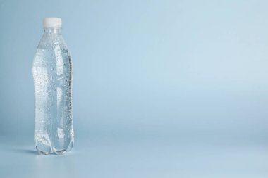 Açık mavi zemin üzerinde plastik su şişesi, metin için boşluk