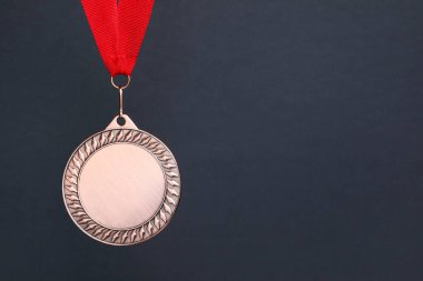 Koyu gri arka planda kırmızı kurdeleli bronz madalya, metin için boşluk