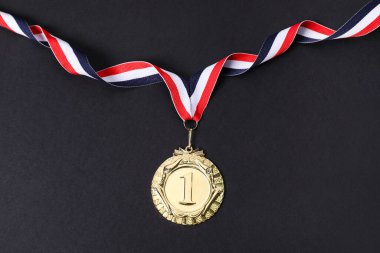 Siyah arka planda çizgili kurdeleli altın madalya, üst görünüm