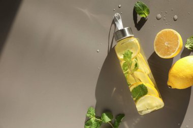 Şişe içinde nane aromalı limon suyu, taze yapraklar ve açık kahverengi masada meyveler, düz yatak. Metin için boşluk
