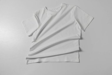 Açık arkaplanda bir tişört, üst görünümde.