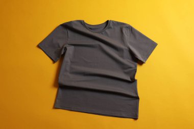 Sarı arkaplanda gri bir tişört, üst manzara.