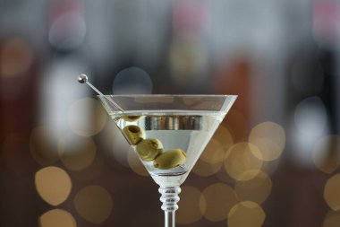Arka planda bulanık zeytinli martini kokteyli, yakın plan. Bokeh etkisi
