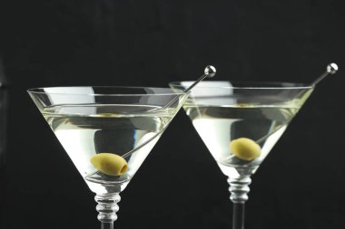 Siyah arka planda zeytinli martini kokteyli, yakın plan.