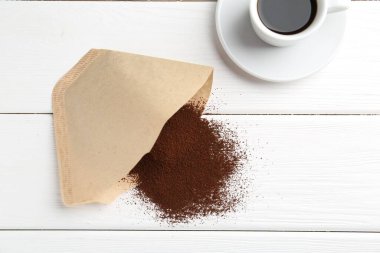 Kağıt filtre, öğütülmüş kahve ve bir bardak içki beyaz ahşap masada, düz yatıyordu.