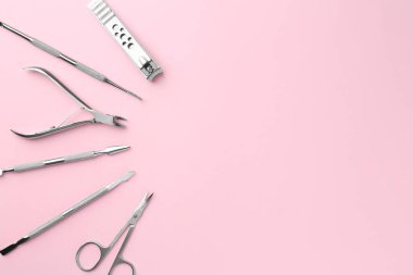 Pembe arka planda pedikür aletleri seti, düz yatış. Metin için boşluk
