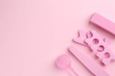 Pembe arka planda pedikür aletleri seti, düz yatış. Metin için boşluk