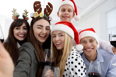 Gülümseyen meslektaşlar ofiste Noel partisinde selfie çekiyorlar.