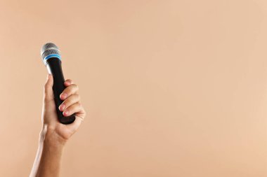 Bej arka planda mikrofonu olan adam, yakın plan. Metin için boşluk