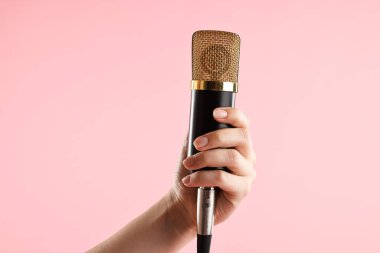 Pembe arka planda mikrofonu olan kadın, yakın plan.