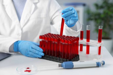 Laboratuvar testi. Doktor kan örneğiyle birlikte test tüpünü kapalı bir masada, yakın plan çekimde alıyor.
