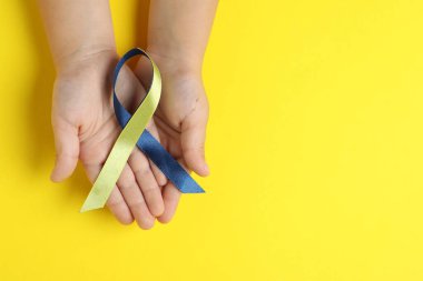 Arka planda sarı ve mavi kurdeleli çocuk, üst manzara. Down sendromu farkındalığı