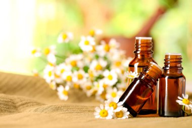 Gerekli yağ şişeleri ve kumaş üzerinde papatya çiçekleri. Metin için boşluk